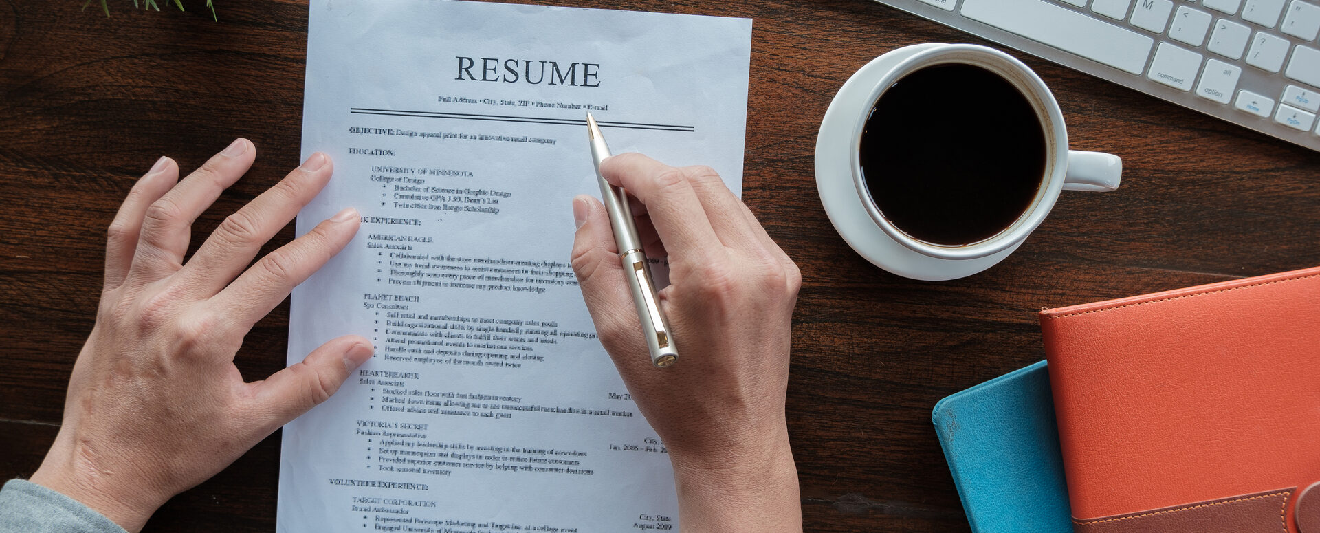 New graduate student holding resume application with pen coffee cup keyboard and notebook for applying for a job.